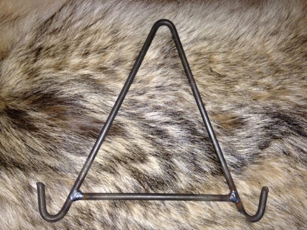 A triangle shaped metal holder on top of a fur.