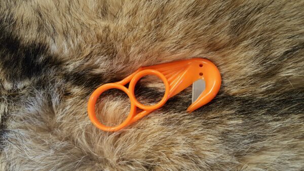 A pair of orange scissors on top of a fur.